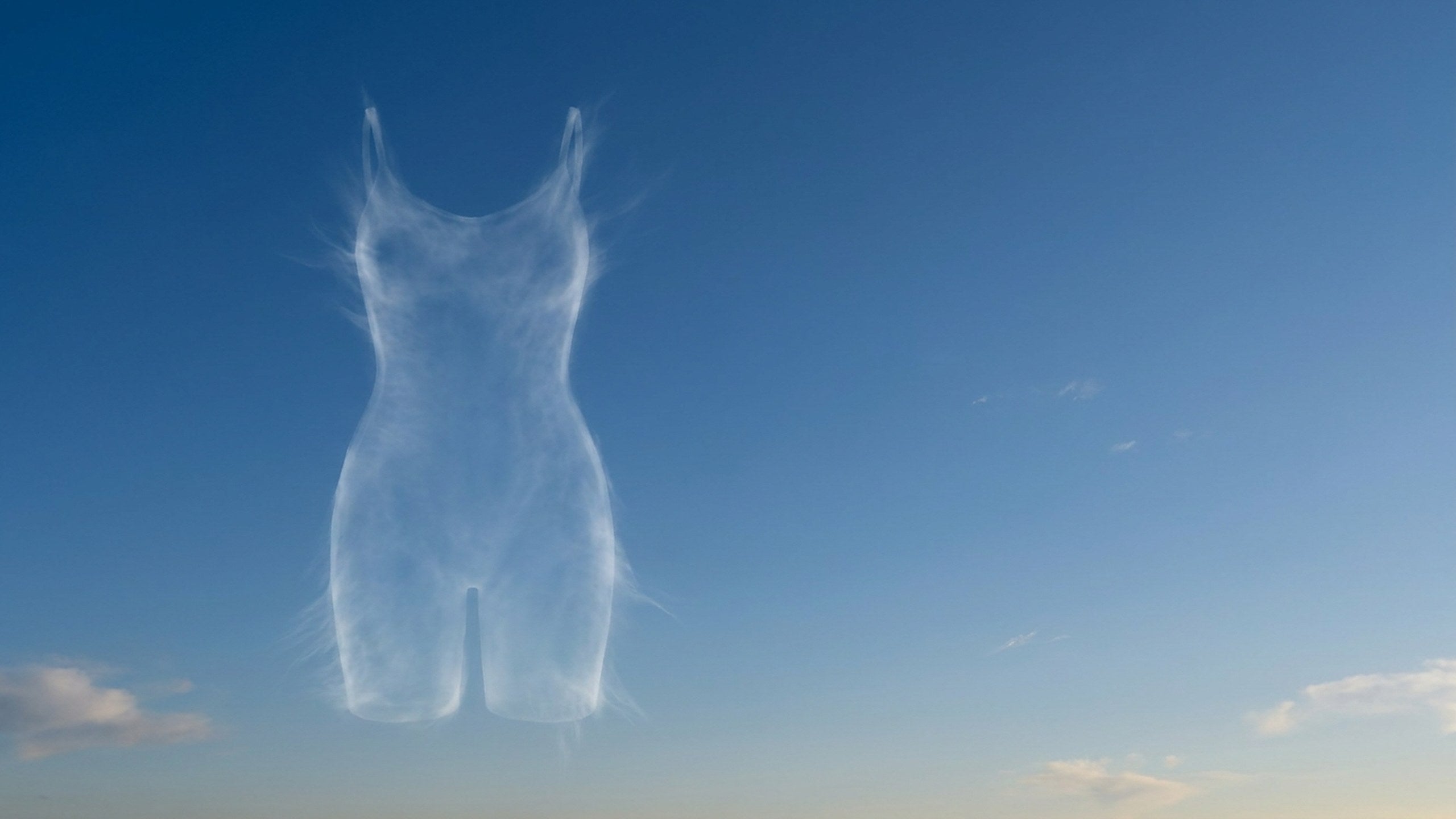 A bodysuit outlined in a thin veil of cloud against a deep blue sky